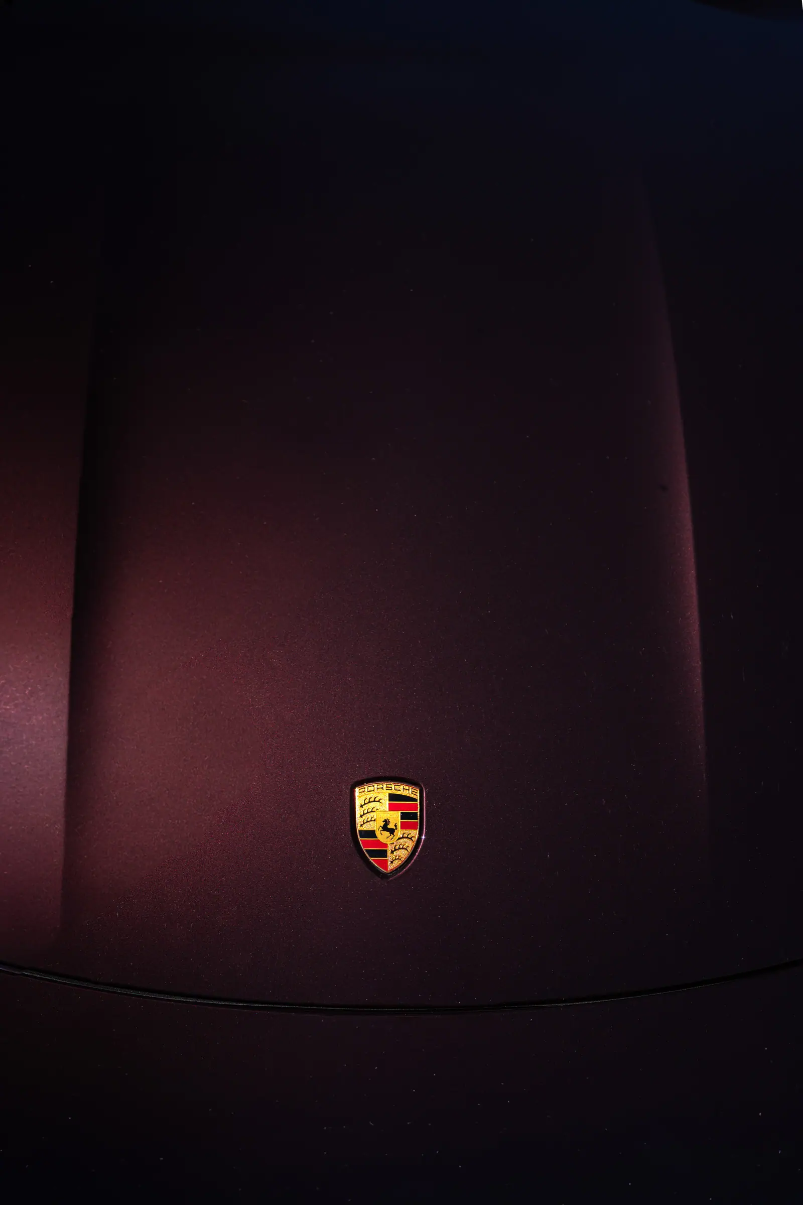 Porsche crest on a matte burgundy bonnet